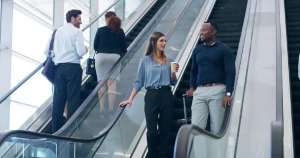 Back to work after break time. 4k video footage of two young businesspeople coming down the escalator at work. — стоковое видео