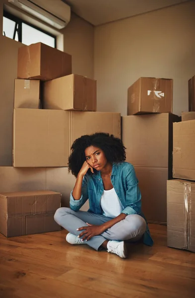 Кто-нибудь, помогите мне. Портрет несчастной молодой женщины, сидящей на земле в окружении картонных коробок в день переезда внутри дома. — стоковое фото