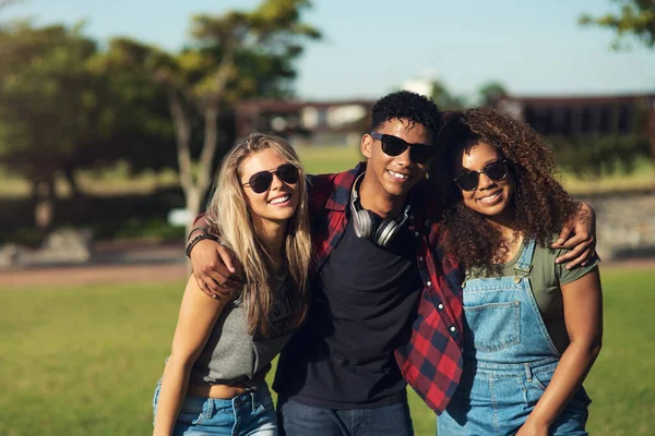 Occhiali da sole. Ritratto di un gruppo di giovani amici allegri che posano insieme per una foto mentre indossano occhiali da sole fuori in un parco. — Foto Stock