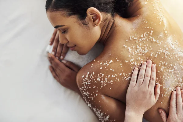 Esfregando a pele morta para revelar um novo tu. Tiro de uma jovem mulher recebendo uma massagem esfoliante em um spa. — Fotografia de Stock
