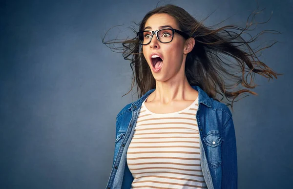Surprise. Shot of a happy young woman with air being blown in her face in studio. — Stock Photo, Image