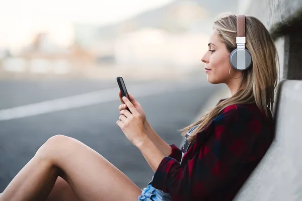 Questa e 'ufficialmente la mia preferita per questa settimana. Girato di una giovane donna attraente seduta ad ascoltare musica sul suo cellulare in città. — Foto Stock