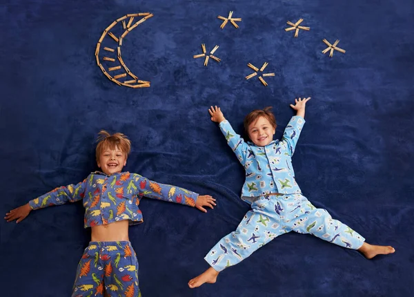 Rapazinhos com grandes sonhos. Dois meninos deitados debaixo de uma lua imaginária e estrelas. — Fotografia de Stock