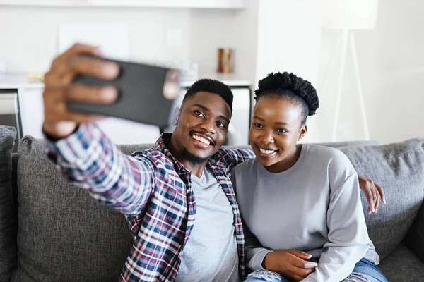 Momentos simples transformados em belas lembranças. Tiro de um jovem casal tomando selfies juntos em casa. — Fotografia de Stock