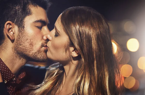 De delar en passionerad kärlek. Skjuten av ett ungt par dela en romantisk kyss tillsammans utanför på natten. — Stockfoto