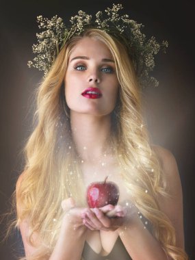 One bite and it could all be yours. Studio shot of a gorgeous young woman offering a magical red apple against a dark background. clipart