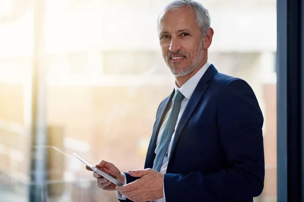 Hålla koll på digitala företagstrender. Porträtt av en leende mogen affärsman som använder en digital surfplatta stående på ett kontor. — Stockfoto