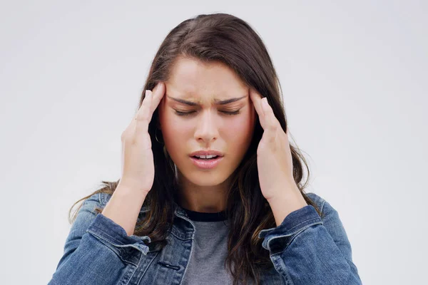 Ik heb volledige stilte nodig als ik me zo voel. Schot van een jonge vrouw die haar hoofd vasthoudt terwijl ze hoofdpijn heeft tegen een grijze achtergrond. — Stockfoto