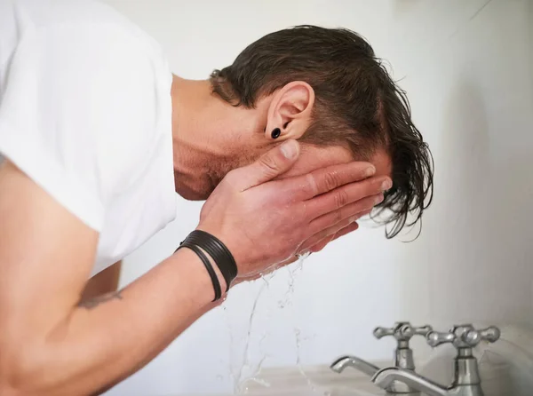 Sabahları ferahlıyorum. Genç bir adamın banyo lavabosunda yüzünü yıkarken fotoğrafı.. — Stok fotoğraf