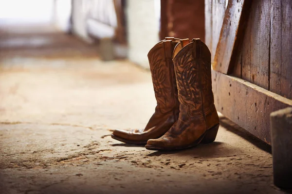 Ein weiterer Tag ist vorbei. Aufnahme eines Paares Cowboystiefel in einer Scheune. — Stockfoto