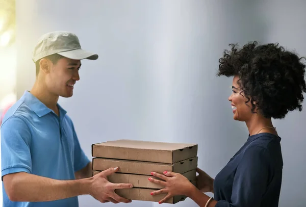 Обережно, вони все ще гарячі. Знімок щасливої бізнес-леді, яка приймає доставку піци від доставленого чоловіка в офісі . — стокове фото