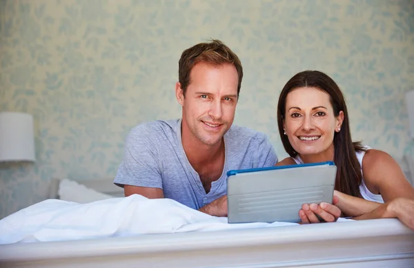 Entré al modo fin de semana. Retrato de una pareja adulta usando una tableta digital mientras se relaja en la cama juntos. — Foto de Stock
