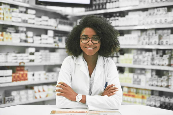Whats on the menu today. Portrait of a cheerful young female pharmacist standing with arms folded while looking at the camera in a pharmacy. — Stock Photo, Image