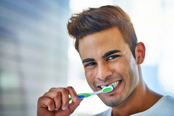 La salud de mi boca depende de ello. Retrato de un joven feliz cepillándose los dientes en casa. — Foto de Stock