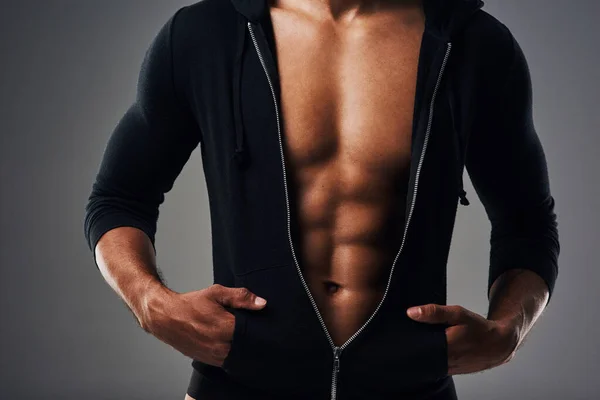 Es demasiado sexy para la ropa. Foto recortada de un joven musculoso irreconocible posando en una sudadera con capucha con cremallera sobre un fondo gris. —  Fotos de Stock