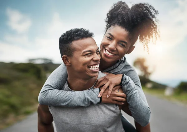 Kom dit... tillsammans. Beskuren bild av en stilig ung idrottsman gris backar upp sin atletiska unga flickvän utanför. — Stockfoto