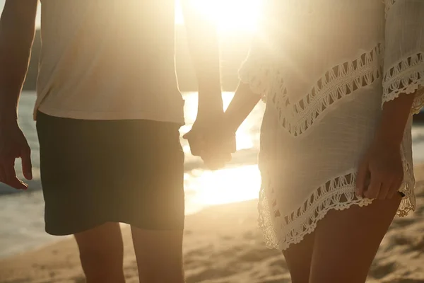 Kéz a kézben a homokban. Lelőttek egy szerető fiatal párt a parton naplementekor.. — Stock Fotó