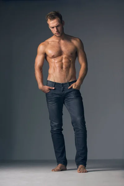 Brütende Männlichkeit. Studioaufnahme eines hemdlosen, muskulösen Mannes in Jeans. — Stockfoto