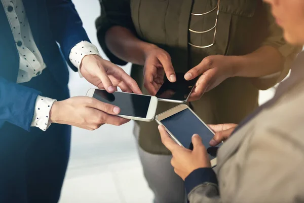 Gemeinsam bessere Verbindungen schaffen. Schnappschuss einer Gruppe unkenntlich gemachter Geschäftsleute, die ihre Mobiltelefone gemeinsam in einem Büro benutzen. — Stockfoto