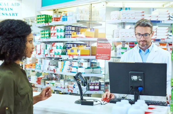 Kijelentkezem. Vágott kép egy jóképű, érett férfi gyógyszerészről, aki segít egy női vásárlónak a gyógyszertárban.. — Stock Fotó