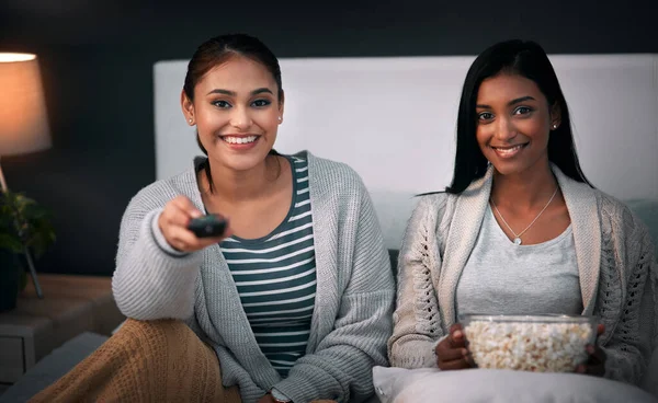 Its movie night. Shot of two young women eating popcorn while watching a movie at home.