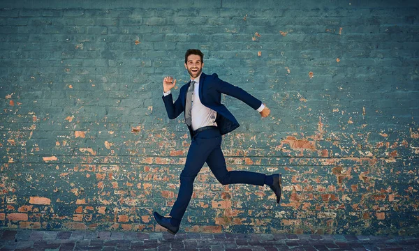 Begierig auf Erfolg. Porträt eines jungen Geschäftsmannes, der gegen eine Ziegelwand springt. — Stockfoto