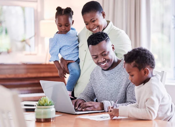 Aile sana güçlü ve dik durman için kökler verir. Evde dizüstü bilgisayara bakarken bir araya toplanmış mutlu bir ailenin fotoğrafı.. — Stok fotoğraf
