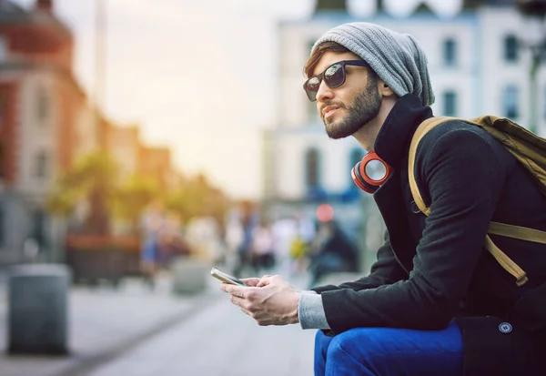 Kilometerweit entfernt in der Mitte von allem. Schuss auf jungen Mann mit Handy in der Stadt. — Stockfoto