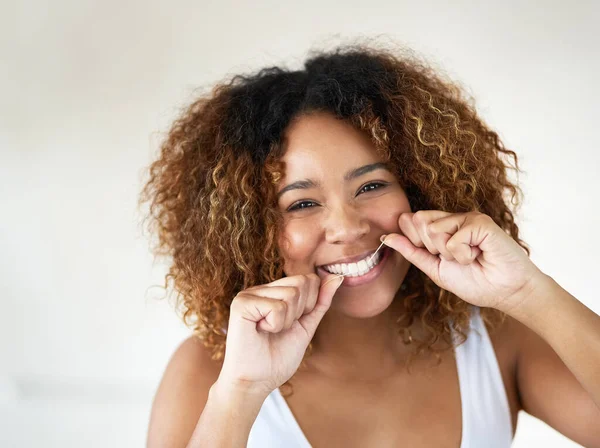 O fio dental é uma parte essencial do cuidado com os dentes. Tiro de uma jovem mulher que usa fio dental nos dentes. — Fotografia de Stock