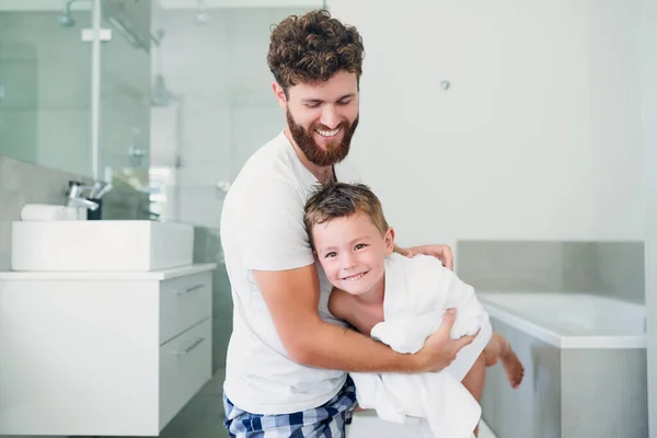 Trochu jsem se bavil sušením. Vystřižené záběr na mladého pohledného otce sušení jeho rozkošný malý syn po koupeli v koupelně doma. — Stock fotografie