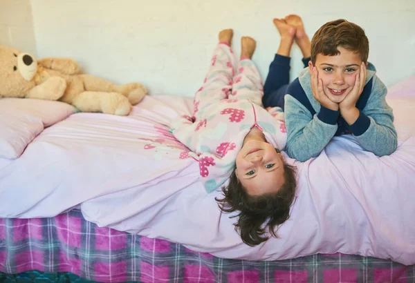 Sie verbindet eine besondere Geschwisterbindung. Aufnahme von zwei jungen Geschwistern, die zusammen auf einem Bett zu Hause liegen. — Stockfoto