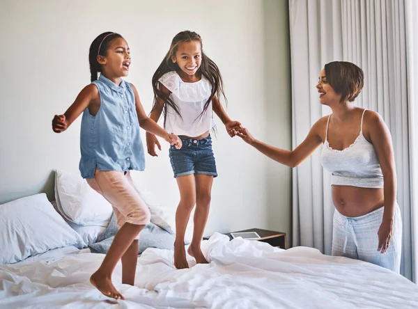 Rondspringen. Shot van een vrolijke jonge familie springen rond op een bed samen thuis tijdens de dag. — Stockfoto