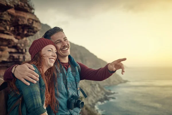 Ahí es donde empezamos. Recortado disparo de una joven pareja cariñosa teniendo en la vista desde una cima de la montaña. — Foto de Stock