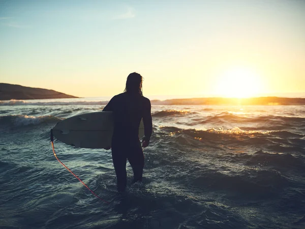 C'est la maison pour moi. Vue arrière d'un jeune homme portant une planche de surf à la plage. — Photo