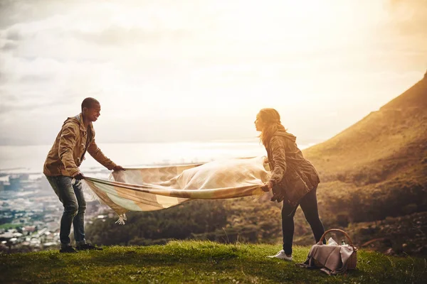 Este é o local perfeito para um piquenique. Tiro de dois jovens amigos montando um piquenique lá fora. — Fotografia de Stock