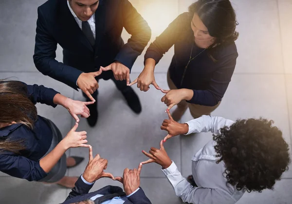 Aprovechando su sinergia. Alto ángulo de tiro de un grupo de compañeros de trabajo haciendo una forma con sus manos en la oficina. — Foto de Stock