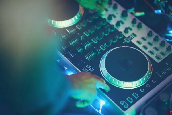 Subiendo el volumen. Fotografía de un DJ no identificable haciendo música en un club nocturno. — Foto de Stock