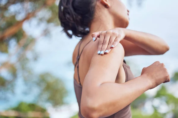 This doesnt feel right. Shot of a young woman experiencing shoulder pain while exercising outdoors.