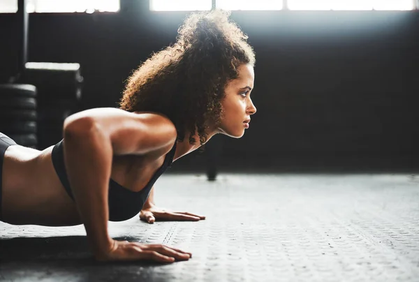 Sê o melhor que puderes. Tiro de uma jovem mulher fazendo flexões em um ginásio. — Fotografia de Stock