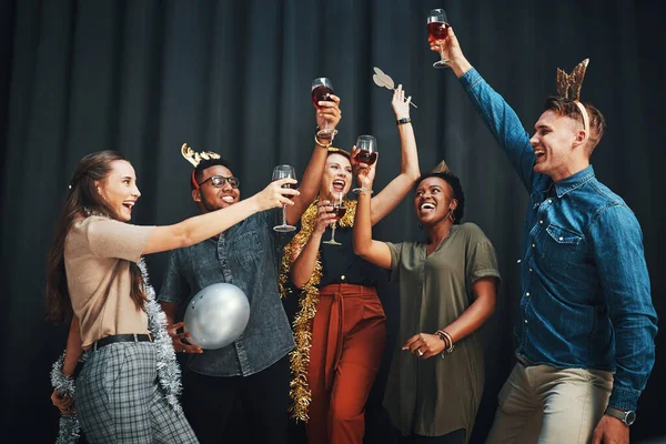 Fiesta hasta el año nuevo. Foto recortada de un grupo diverso de amigos de pie y sosteniendo copas de vino para un brindis en Año Nuevo. — Foto de Stock