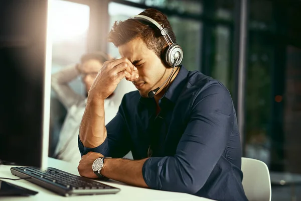 Het was een stressvolle dag op het werk. Foto van een jonge call center agent die gestresst kijkt tijdens het werken in een kantoor. — Stockfoto