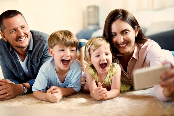 Δεν χρειάζεται να ζητήσει από τα παιδιά δύο φορές για να πάρετε μια selfie. Φωτογραφία μιας χαρούμενης νεαρής οικογένειας που βγάζει φωτογραφίες μαζί στο σπίτι. — Φωτογραφία Αρχείου