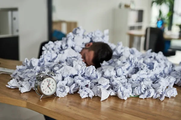 La pressione pesa molto. Girato di un giovane uomo d'affari circondato da pile di carta in un ufficio. — Foto Stock