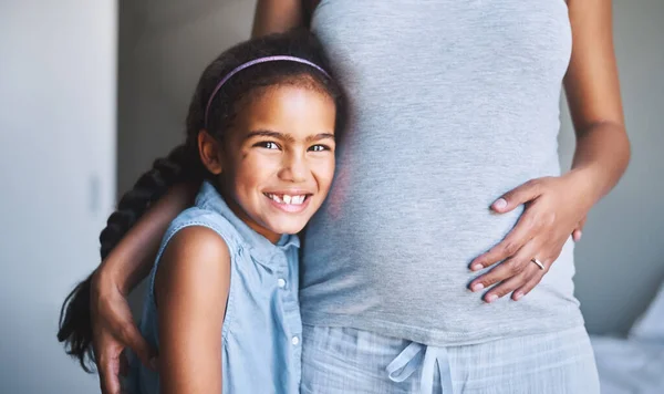 Хочу познайомитися з моїм новим братом. Портрет веселої маленької дівчинки, що стоїть з руками навколо її вагітної іншої вдома протягом дня . — стокове фото