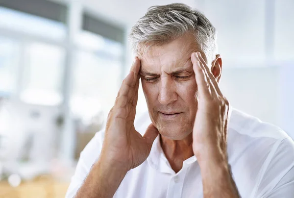 生産的であることを試みるが、この頭痛は助けることに抵抗する。仕事で頭痛に苦しんでいる成熟したビジネスマンのショット. — ストック写真