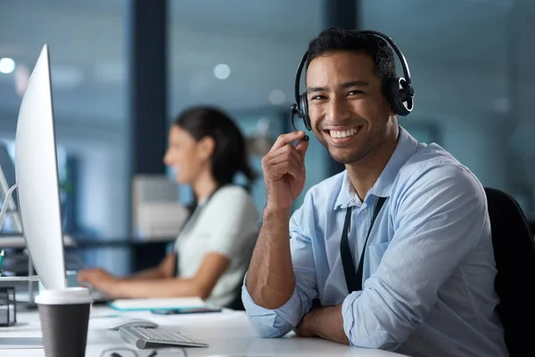 Spokojenost našich zákazníků říká všechno. Portrét mladého muže používajícího sluchátka a počítač v moderní kanceláři. — Stock fotografie
