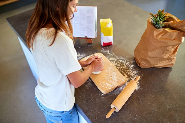 Fatto in casa è meglio. Una giovane donna impastare pasta nella sua cucina. — Foto Stock