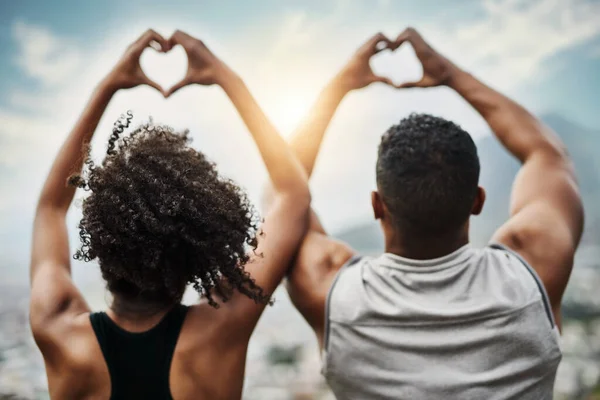 Corações felizes. Foto retrovisor de um jovem casal esportivo fazendo formas de coração com as mãos enquanto se exercita ao ar livre. — Fotografia de Stock