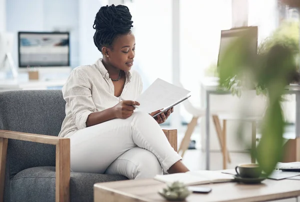 These documents need some amending. Shot of a businesswoman using her digital tablet while reading paperwork. — Stock Photo, Image