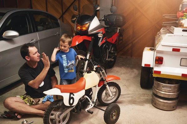 Mission accomplie. Prise de vue d'un père et d'un fils réparant un vélo dans un garage. — Photo